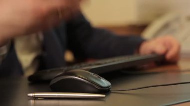 Male hand, close-up. A man works with a computer mouse and types on a keyboard. Writing pen in the foreground. Hand gesture. The teacher explains and tells.