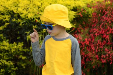 Positive boy in a yellow panama hat and sunglasses. Child 5 years old. The boy rejoices in the journey, going to the atrankion park, preparing for school. Emotions on the face. Resort for children, summer camp, extended day group
