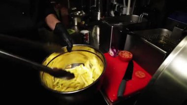 Craft burger. Mage's gloved hands take French fries with tongs. The chef puts freshly cooked french fries on a plate. Burger and french fries. Fast food restaurant menu.