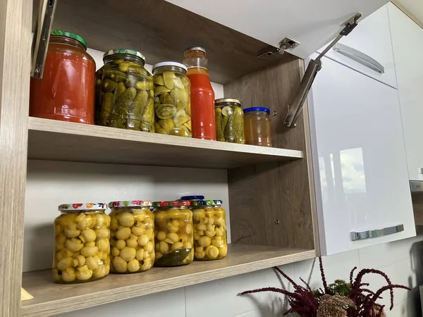 Preservation for the winter, pickled vegetables in jars. Pickled cucumbers, tomato juice, marinated champignon mushrooms. Homemade pickles, autumn harvest.