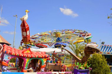 Klasik Luna Parkı, eski usul binişler. Atlıkarınca, çocuk treni, paraşütler, lunapark. Parlak resim - çocuklarla tatil. Metin için yer.