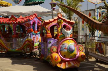 Klasik Luna Parkı, eski usul binişler. Atlıkarınca, çocuk treni, paraşütler, lunapark. Parlak resim - çocuklarla tatil. Metin için yer.
