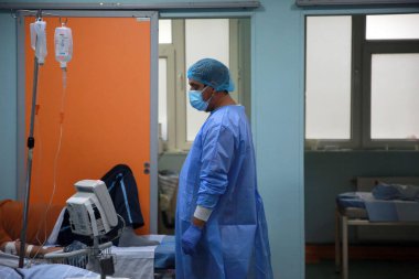 BUCHAREST, ROMANIA - 15 Ekim 2021: Kişisel Koruyucu Ekipman (PPE) giyen bir tıp çalışanı, Coronavirus salgını nedeniyle aşırı kalabalık olan St. Pantelimon hastanesinin acil servisindeki hastalara bakıyor.