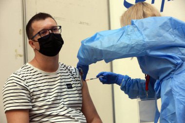 BUCHAREST, ROMANIA - 23 Ekim 2021 Bükreş 'teki Ulusal Kütüphane Aşılama Maratonu sırasında bir doz COVID 19 aşısı uygulayan bir tıp çalışanı.