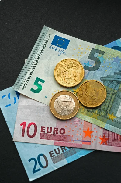 Euro Bank notes and coins, includes 20,10- and 5-euro notes, bills and 1 euro,50 and 20 cent coins on black background