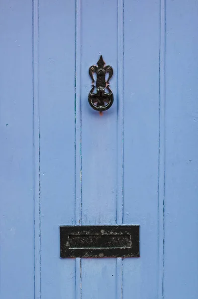 Old, blue painted door with knocker and letter box, close-up, background