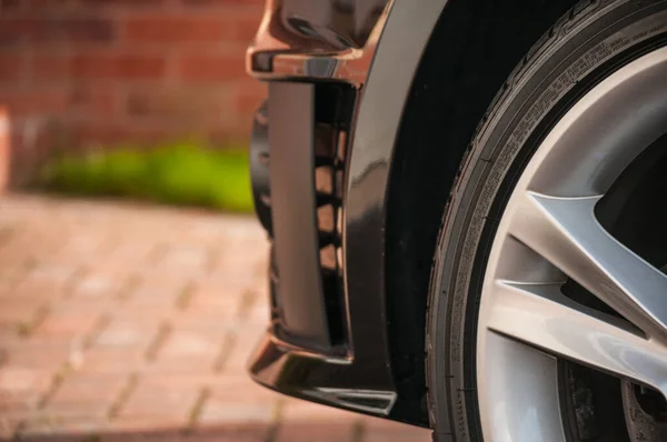 Tyre with silver alloy wheel, close up, black bodywork