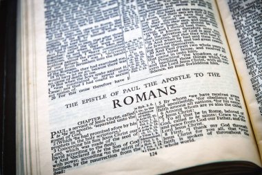 Close up of Holy Bible page, shallow depth of field with focus on book chapter heading, Romans