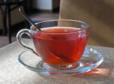 Kafenin içindeki masada duran siyah çay bardağı.       