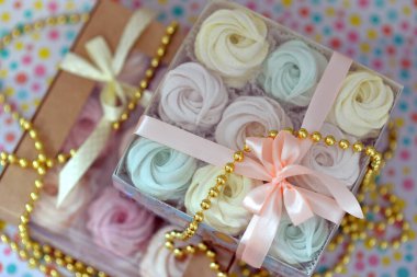 Marshmallow hediye kutusu marshmallow sarısı, nane ve pembe, hediye kutusunda. Pembe fiyonk ve kurdeleyle süslenmiş. Kutular parlak bir arka planda, benekli. Altın boncuklar. 