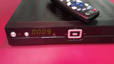 Kırmızı arkaplan üzerinde izole edilmiş uydu ve IP TV STB alıcısı ve uzaktan denetleyici