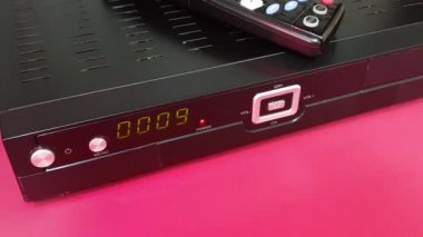 Kırmızı arkaplan üzerinde izole edilmiş uydu ve IP TV STB alıcısı ve uzaktan denetleyici
