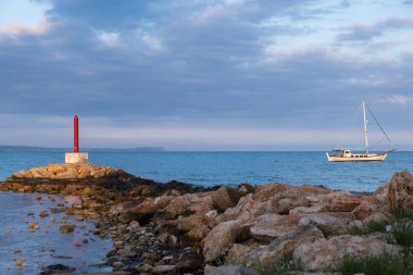 Lighthouse and Sailboat bathed in afternoon light in Potamos Liopetri fishing village in the Mediterranean island of Cyprus