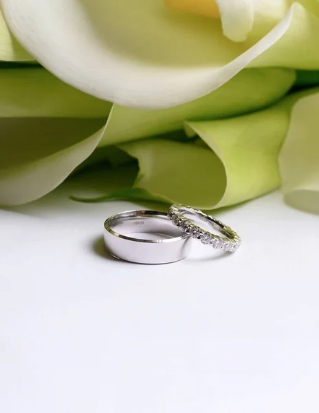 Stylish wedding rings made of white gold on a background of a bouquet of calla lilies — 스톡 사진