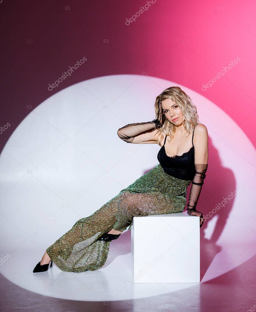 Blonde girl posing on a red circle background in the studio