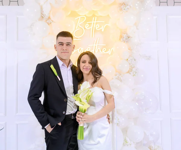 Красива молода пара позує на фоні фото декору з білими кульками — стокове фото