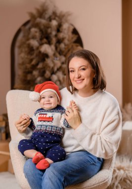 Genç aile annesi ve oğlu yeni yıl ağacının arka planında poz veriyorlar.