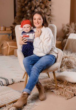 Genç aile annesi ve oğlu yeni yıl ağacının arka planında poz veriyorlar.