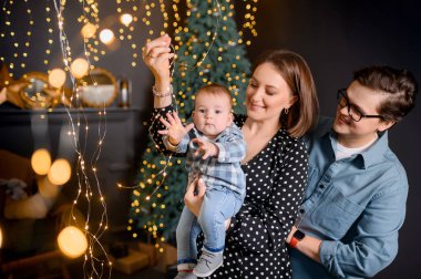 Genç aile babası, anne oğlu Noel ağacı dekorunda çocuk.
