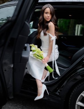 Siyah saçlı güzel gelin arabadan iner.