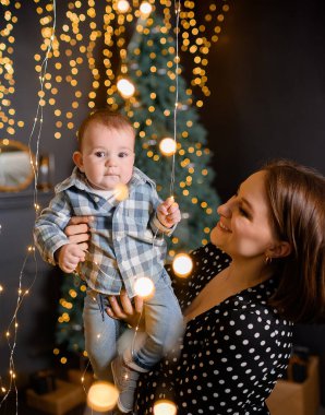 Young family mom son toddler on Christmas tree decor background