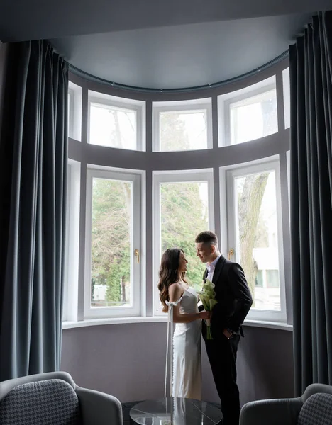 Belo par de noivas posando no fundo de uma janela — Fotografia de Stock