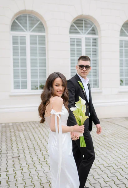 Beautiful young newlywed couple in sunglasses walking — Stok Foto