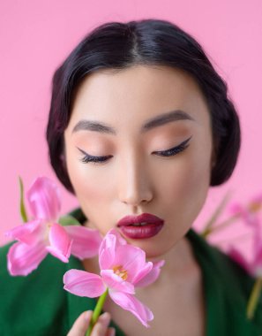 Close up portrait a beautiful Chinese woman with fresh pink tulips
