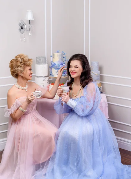 İki orta yaşlı arkadaş dedikodu yapıyor ve kahve içiyor.