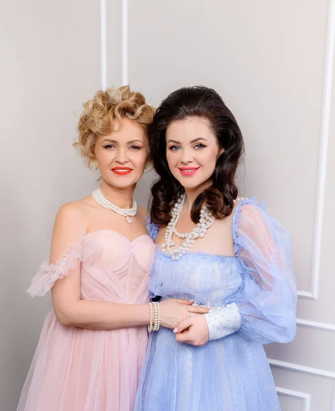 Gece elbiseli iki orta yaşlı bayan arkadaş sarılıyor.