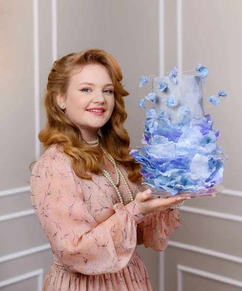 Young blonde girl holding a big blue cake — Stock Photo, Image