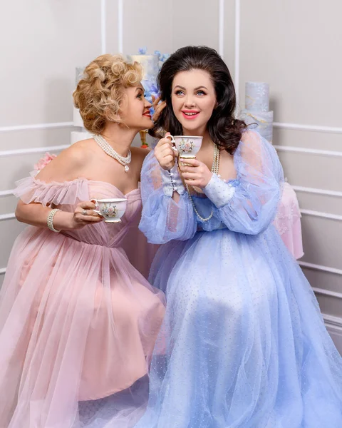 İki orta yaşlı arkadaş dedikodu yapıyor ve kahve içiyor.