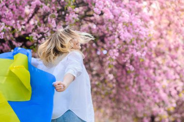 Beyaz gömlekli güzel sarışın kız Ukrayna bayrağını taşıyor. 