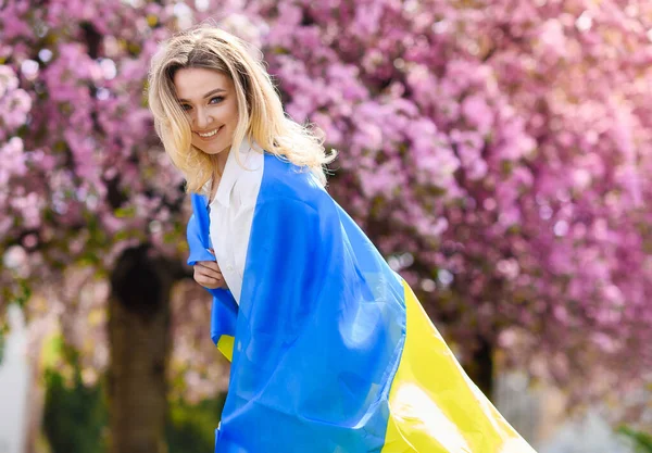 Gyönyörű szőke haj lány fehér ingben tartja a zászló Ukrajna — Stock Fotó