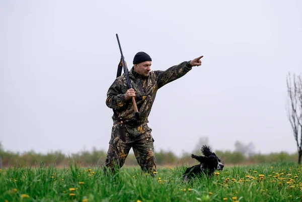 Male hunter with a gun on his shoulder with a dog Russian spaniel hunt — Stockfoto