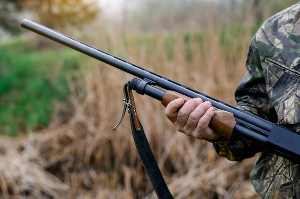 Gewehr in den Händen eines Jägers auf Schilfgrund — Stockfoto