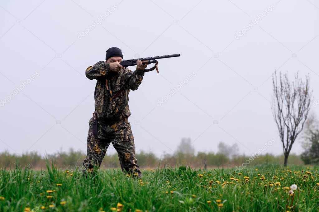 A male hunter with a rifle hunts and aims
