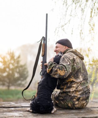 Erkek avcı, bir Rus spanyeliyle köprüde oturuyor. 