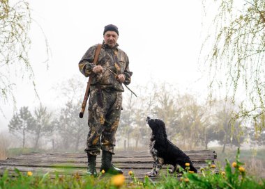 Hunter arka planında bir köpek ve köprü olan bir dal uçuruyor.