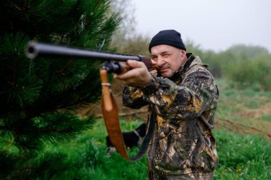 Hunter sisli bir gölün arka planına bir tüfek doğrultuyor.