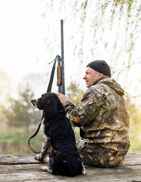 Male hunter sitting on a bridge with a Russian Spaniel — Stockfoto