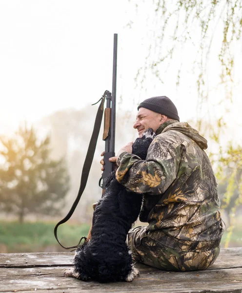 Erkek avcı, bir Rus spanyeliyle köprüde oturuyor. 