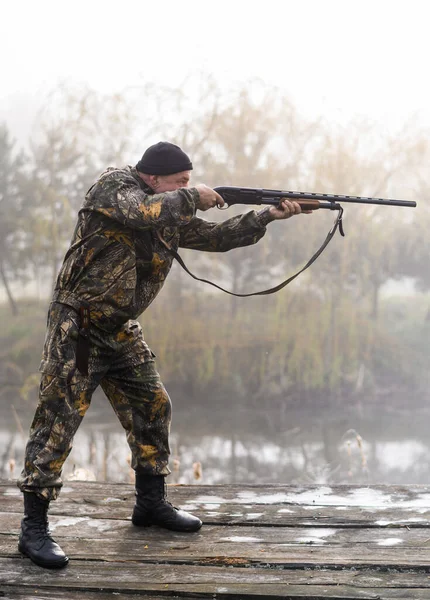 Ein männlicher Jäger mit Gewehr jagt und zielt vor dem Hintergrund von Schilf — Stockfoto