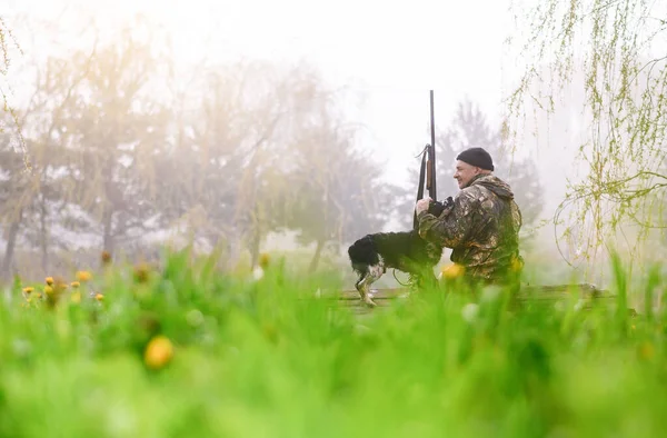 Männlicher Jäger sitzt auf einer Brücke mit einem russischen Spaniel — Stockfoto