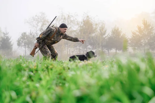 Hunter with a rifle hunting with his dog Russian Spaniel — Stockfoto