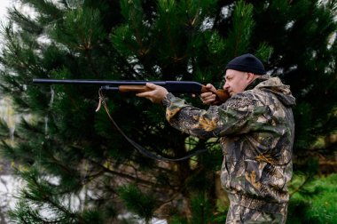 Hunter sisli bir gölün arka planına bir tüfek doğrultuyor.