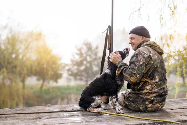 Erkek avcı, bir Rus spanyeliyle köprüde oturuyor. 