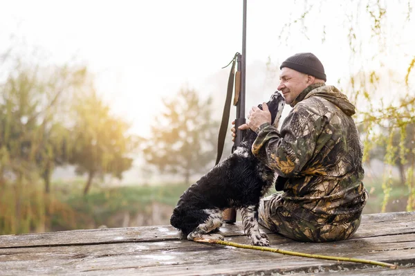 Male hunter sits on a bridge with a Russian spaniel — Stockfoto