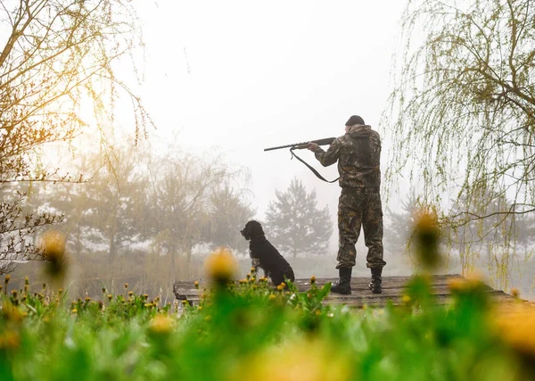 Jäger mit Waffe zielt mit Hund Russischer Spaniel auf Brücke — Stockfoto