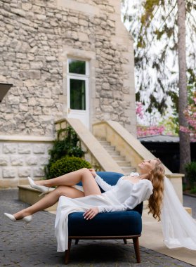 Güzel gelin bir sandalyede oturuyor ve kalenin arka planında poz veriyor.